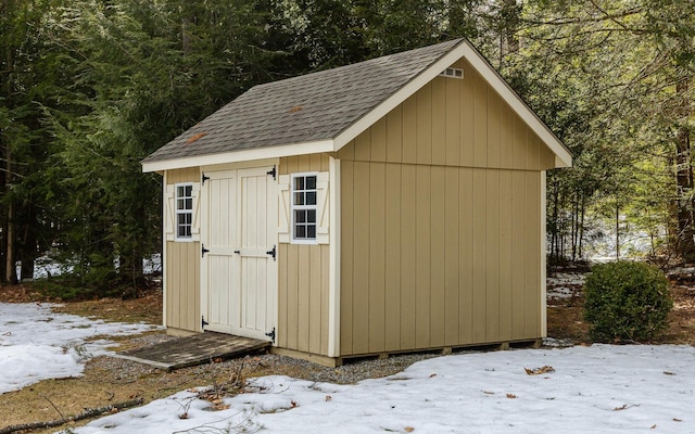 snow covered structure with a shed and an outdoor structure