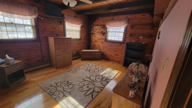 bedroom with a baseboard radiator, wooden walls, wood ceiling, and light wood-style flooring