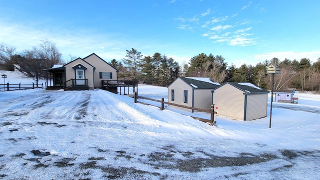 snow covered rear of property featuring a detached garage and an outdoor structure