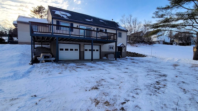 snow covered rear of property with a deck and an attached garage