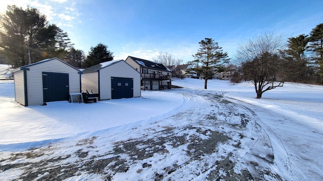 snow covered garage featuring a detached garage and a storage shed