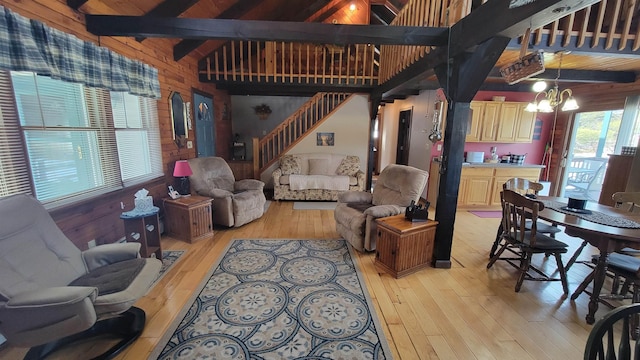 living room with beamed ceiling, light wood-style floors, a chandelier, and wooden walls