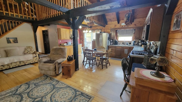 kitchen featuring wooden walls, light countertops, light wood-style flooring, an inviting chandelier, and stainless steel appliances