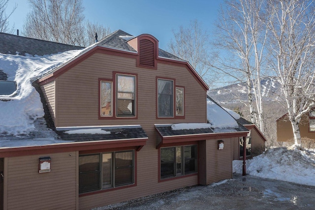 snow covered house featuring a shingled roof