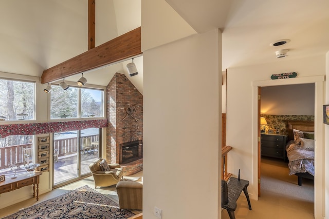 living area with light carpet, beamed ceiling, a brick fireplace, and high vaulted ceiling