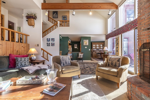 living area with beamed ceiling, a healthy amount of sunlight, high vaulted ceiling, and stairs