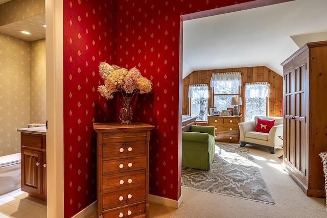 living area featuring vaulted ceiling, wallpapered walls, baseboards, and carpet floors