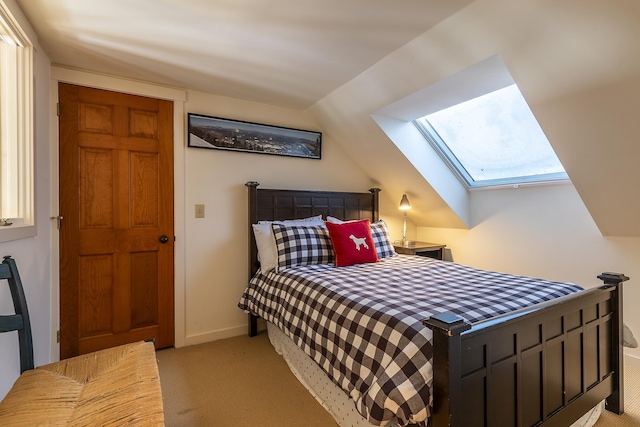 bedroom with vaulted ceiling with skylight, light colored carpet, and baseboards