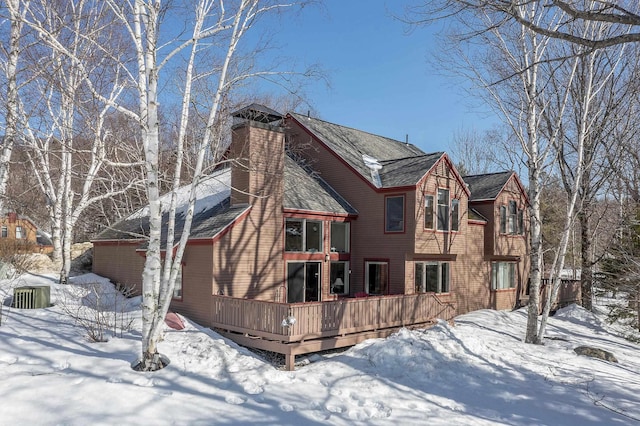 snow covered house with a deck and a chimney