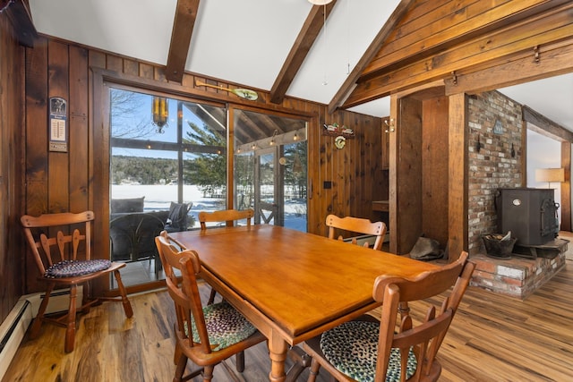 dining room featuring a baseboard heating unit, wooden walls, wood finished floors, and vaulted ceiling with beams