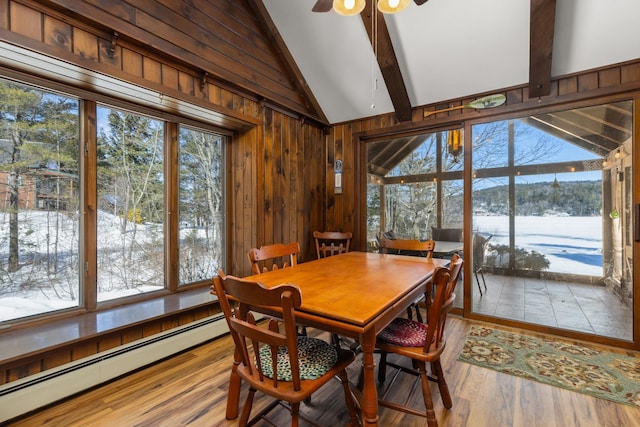 dining area featuring a ceiling fan, lofted ceiling with beams, wood finished floors, wood walls, and baseboard heating