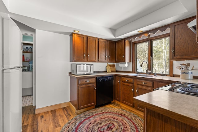 kitchen with white appliances, brown cabinetry, baseboards, light wood finished floors, and a sink