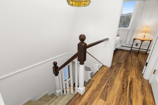 staircase with wood finished floors and baseboard heating