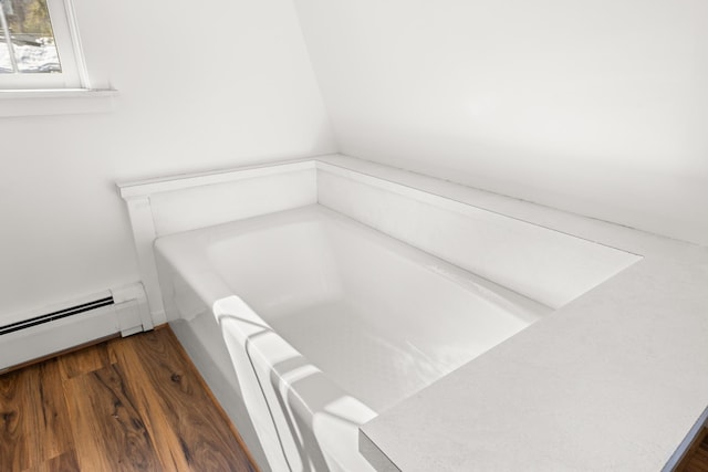 full bath featuring a garden tub, wood finished floors, and baseboard heating