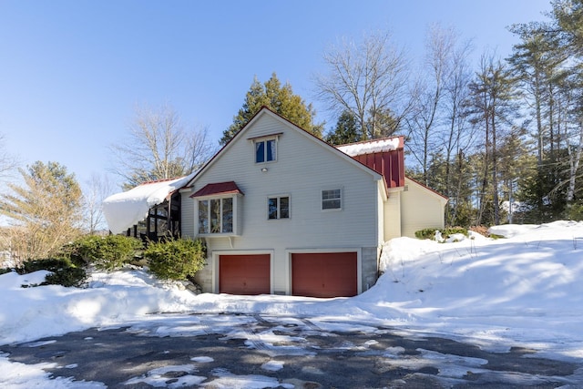 view of snow covered exterior with a garage and board and batten siding