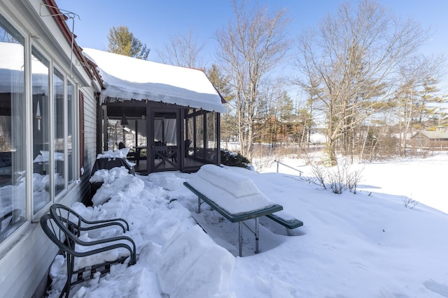 yard layered in snow featuring a sunroom