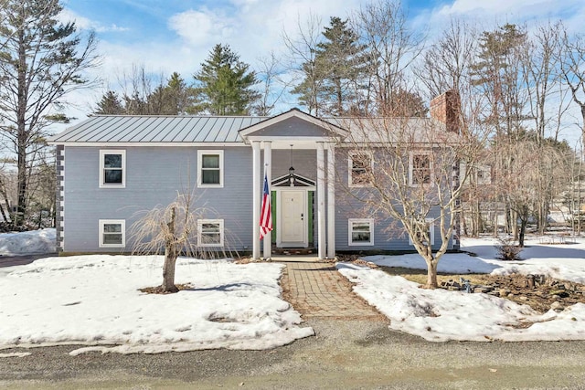 split foyer home featuring a chimney, a standing seam roof, and metal roof