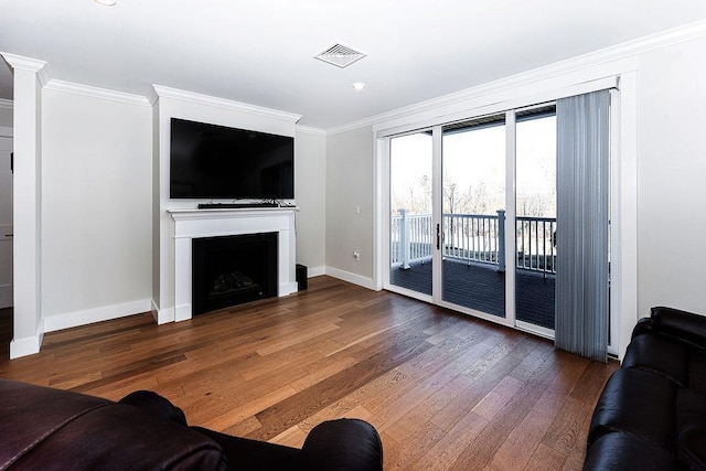 living room with visible vents, hardwood / wood-style floors, a fireplace, crown molding, and baseboards