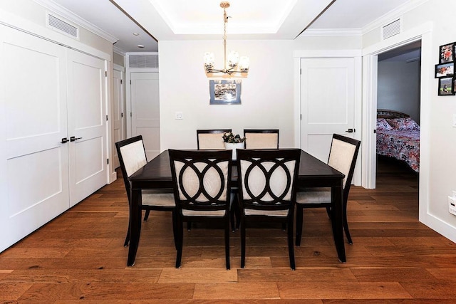 dining space featuring visible vents, a notable chandelier, dark wood finished floors, and crown molding