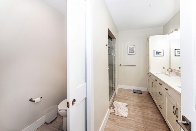 full bath with a shower stall, toilet, baseboards, and double vanity