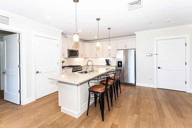 kitchen with visible vents, light wood-style flooring, a sink, appliances with stainless steel finishes, and crown molding