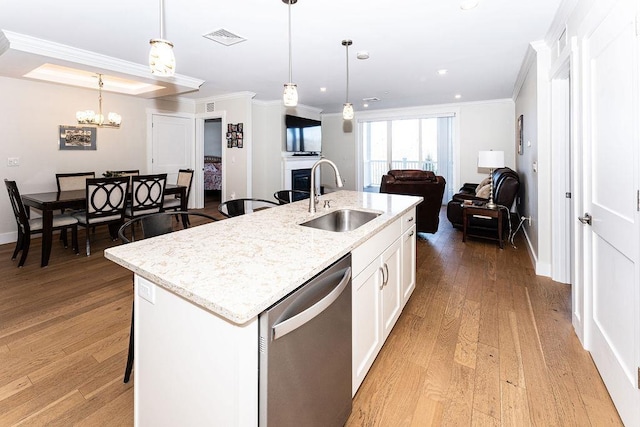 kitchen featuring visible vents, a sink, stainless steel dishwasher, open floor plan, and crown molding