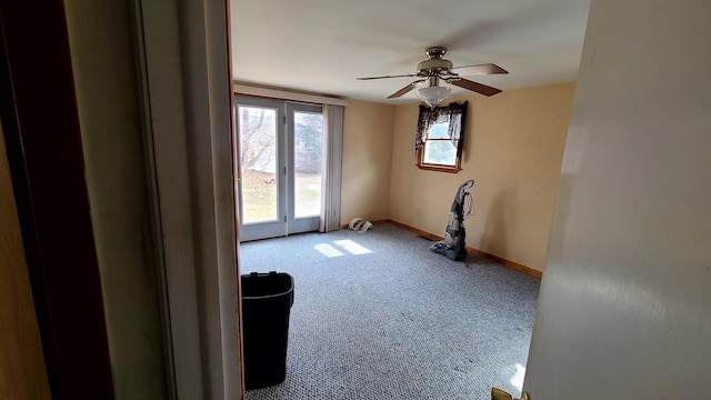 carpeted empty room featuring baseboards and ceiling fan