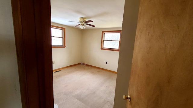 unfurnished room featuring visible vents, a ceiling fan, and baseboards