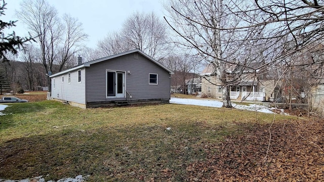 rear view of house featuring entry steps, a chimney, and a yard