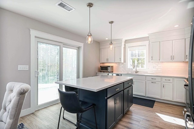 kitchen featuring visible vents, backsplash, white cabinetry, and light countertops