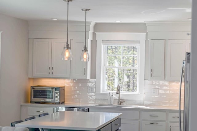 kitchen with a center island, a toaster, dishwasher, light countertops, and a sink