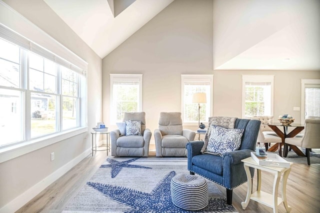 living room featuring light wood-style floors, baseboards, a wealth of natural light, and high vaulted ceiling