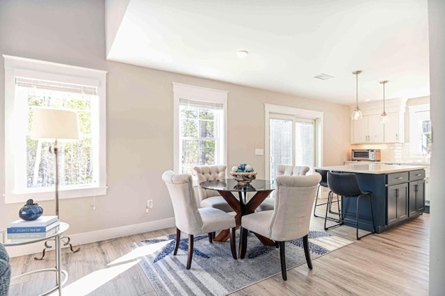 dining space with a toaster, visible vents, light wood-type flooring, and baseboards