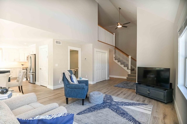 living area with stairway, baseboards, light wood-type flooring, and visible vents