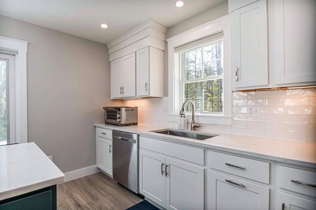 kitchen with dishwasher, white cabinetry, backsplash, and a sink