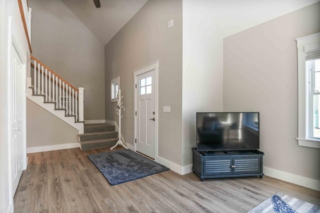 entrance foyer featuring stairs, wood finished floors, baseboards, and high vaulted ceiling