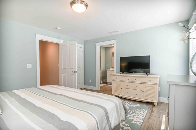 bedroom with visible vents, light wood-type flooring, and baseboards