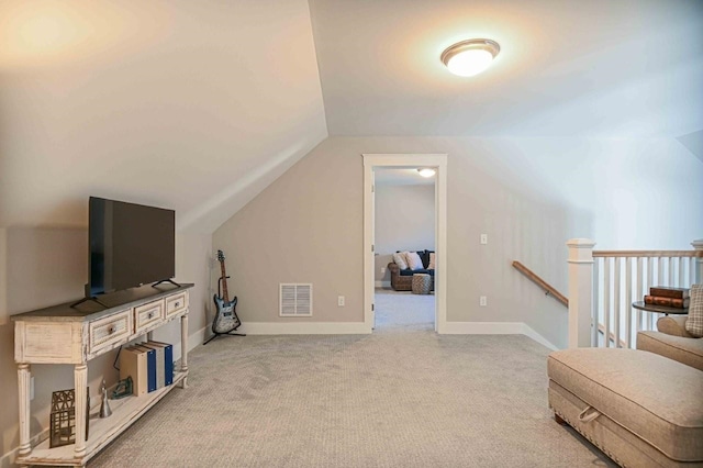 interior space featuring visible vents, an upstairs landing, lofted ceiling, carpet flooring, and baseboards