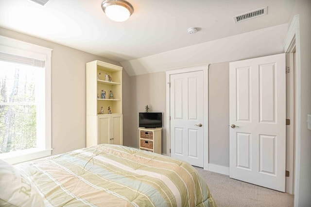 carpeted bedroom with visible vents and vaulted ceiling