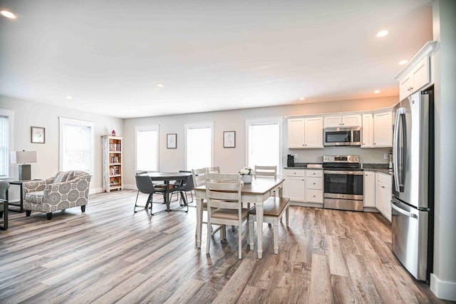 dining room featuring light wood finished floors, recessed lighting, and baseboards