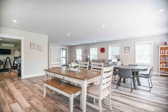 dining room featuring recessed lighting, light wood-style flooring, a wall mounted AC, and baseboards