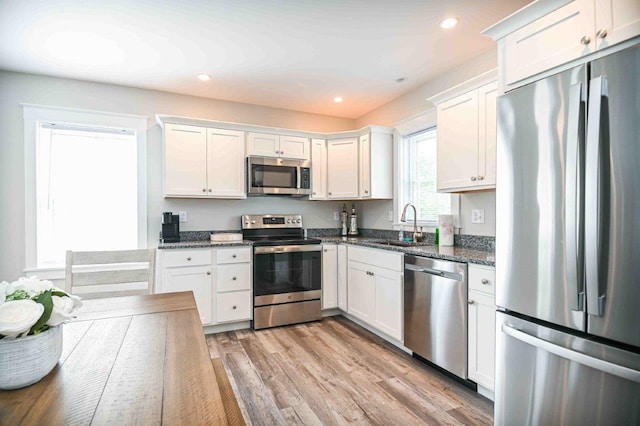 kitchen with a sink, light wood-type flooring, appliances with stainless steel finishes, and white cabinets