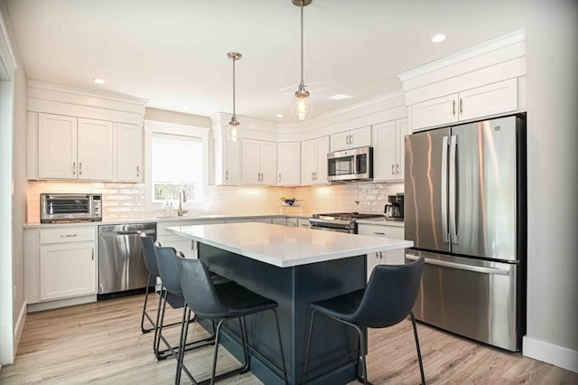 kitchen featuring a toaster, light countertops, light wood-type flooring, appliances with stainless steel finishes, and a kitchen breakfast bar