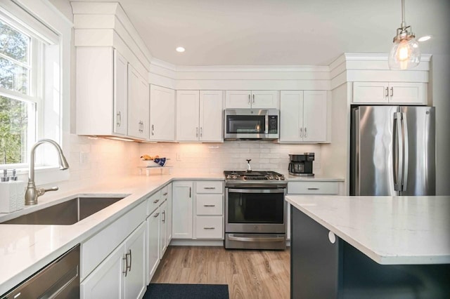 kitchen featuring backsplash, appliances with stainless steel finishes, white cabinetry, and a sink