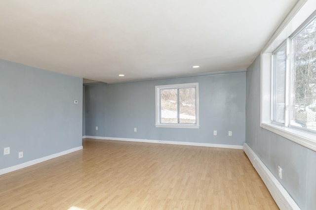 empty room with light wood-type flooring, a baseboard heating unit, baseboards, and recessed lighting