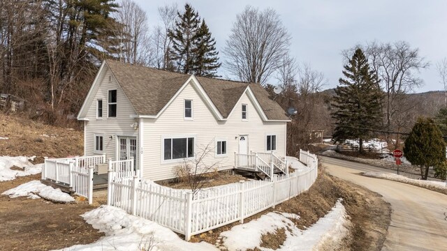 view of front of house with roof with shingles and fence