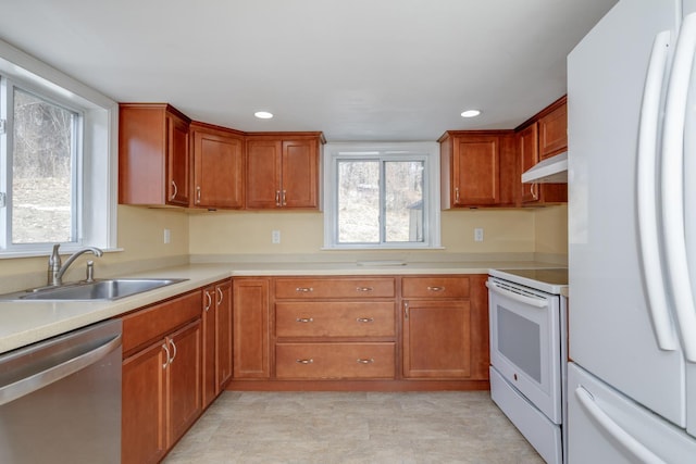 kitchen with white appliances, light countertops, under cabinet range hood, and a sink