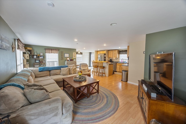 living area featuring recessed lighting, baseboards, and light wood finished floors