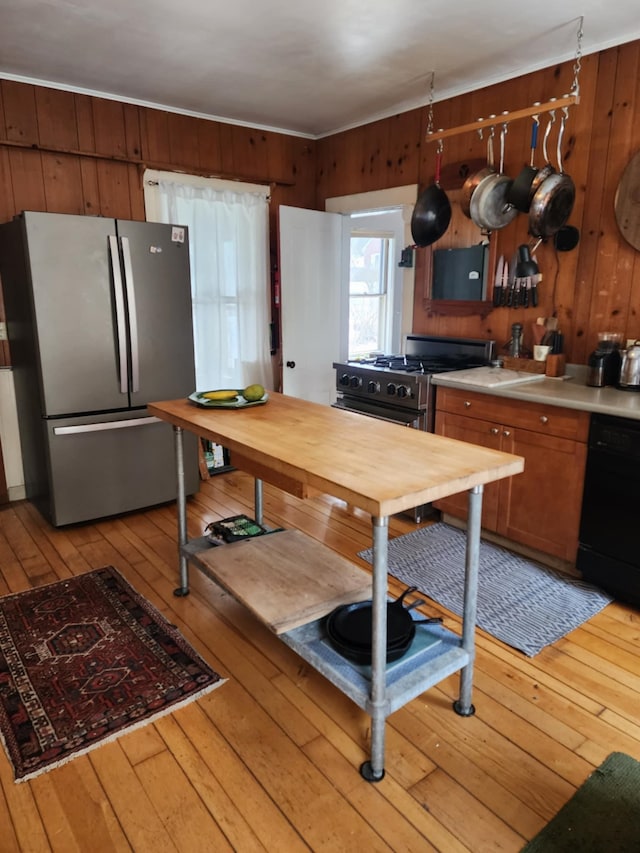 kitchen with light countertops, light wood-style floors, wood walls, and stainless steel appliances