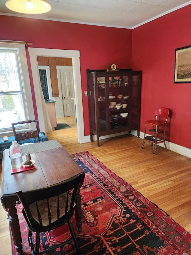 dining area with ornamental molding, baseboards, and hardwood / wood-style floors